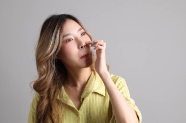 Gri arka planda sıradan giyinmiş Asyalı kadın..