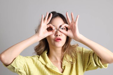 Gri arka planda sıradan giyinmiş Asyalı kadın..