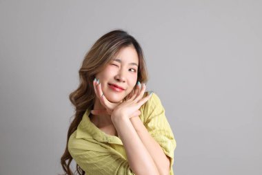 Gri arka planda sıradan giyinmiş Asyalı kadın..