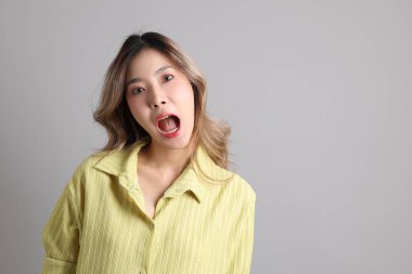 Gri arka planda sıradan giyinmiş Asyalı kadın..