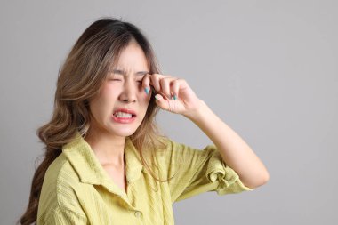 Gri arka planda sıradan giyinmiş Asyalı kadın..