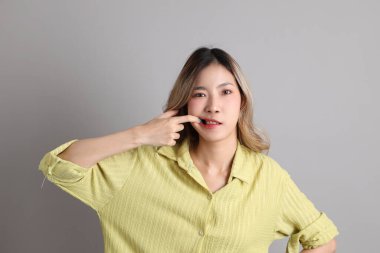 Gri arka planda sıradan giyinmiş Asyalı kadın..