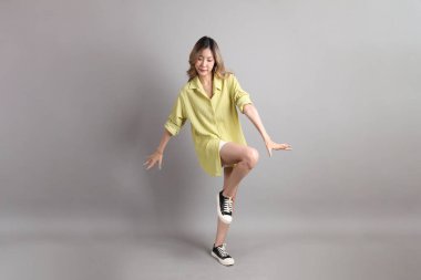 Gri arka planda sıradan giyinmiş Asyalı kadın..