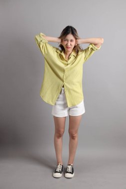 Gri arka planda sıradan giyinmiş Asyalı kadın..