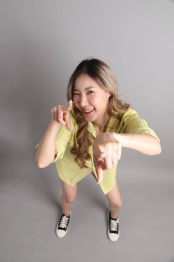 Gri arka planda sıradan giyinmiş Asyalı kadın..