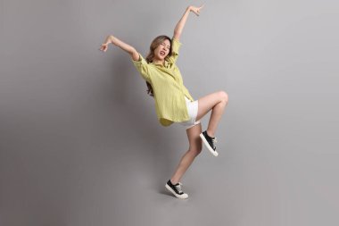 Gri arka planda sıradan giyinmiş Asyalı kadın..