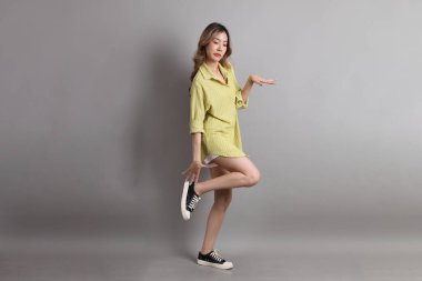 Gri arka planda sıradan giyinmiş Asyalı kadın..