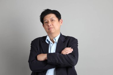 Resmi giyinmiş, gri arka planda duran Asyalı iş adamı..