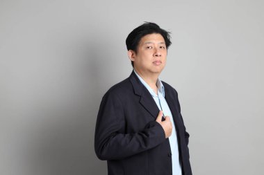 Resmi giyinmiş, gri arka planda duran Asyalı iş adamı..