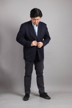 Resmi giyinmiş Asyalı iş adamı gri arka planda giyinin..