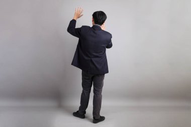 Asyalı iş adamı, resmi giyinmiş. Gri arka planı reddediyor, yasaklıyor, durduruyor..