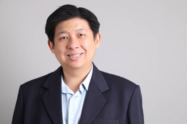 Resmi giyinmiş, gri arka planda duran Asyalı iş adamı..