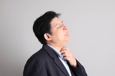 Resmi giyinmiş Asyalı iş adamı gri arka planda giyinin..