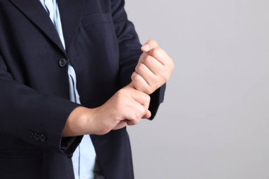 Resmi giyinmiş Asyalı iş adamının elleri gri arka planda..