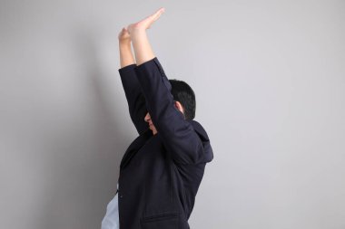 Resmi giyinmiş Asyalı iş adamı. Gri arka planda bitkin bir jestle..