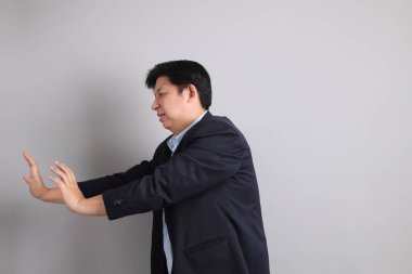 Resmi giyinmiş Asyalı iş adamı. Gri arka planda bitkin bir jestle..