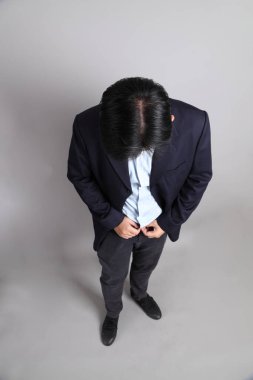 Resmi giyinmiş Asyalı iş adamı gri arka planda giyinin..