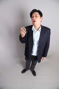 Gri arka planda Uykucu hareketi ile resmi giyinmiş Asyalı iş adamı..