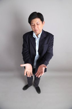 Gri arka planda resmi giyinmiş Asyalı iş adamı..