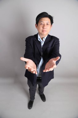 Gri arka planda resmi giyinmiş Asyalı iş adamı..