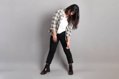 Yetişkin Asyalı kadın gri arka planda duruyor.