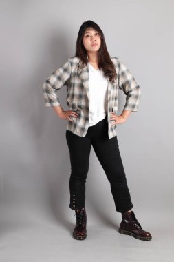 Yetişkin Asyalı kadın gri arka planda duruyor.