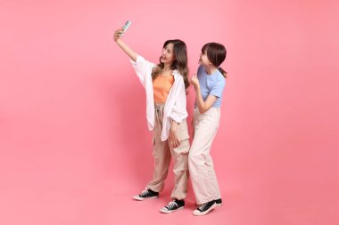 Yetişkin genç arkadaşlar, 20 'li yaşlarda Doğu Asyalı kadınlar pembe arka planda selfie çekiyorlar.. 