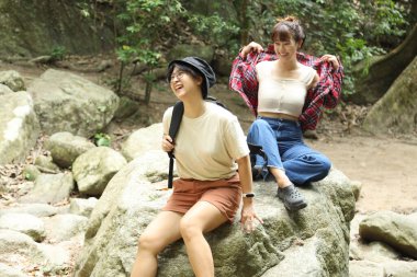 İki Asyalı kardeş yaz mevsiminde gündüz vakti gölün kenarında birlikte vakit geçiriyorlar..