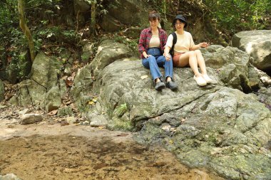 İki Asyalı kardeş yaz mevsiminde gündüz vakti gölün kenarında birlikte vakit geçiriyorlar..