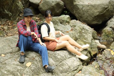 İki Asyalı kardeş yaz mevsiminde gündüz vakti gölün kenarında birlikte vakit geçiriyorlar..