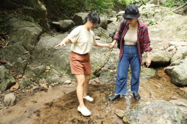 İki Asyalı kardeş yaz mevsiminde gündüz vakti gölün kenarında birlikte vakit geçiriyorlar..