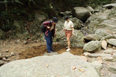 İki Asyalı kardeş yaz mevsiminde gündüz vakti gölün kenarında birlikte vakit geçiriyorlar..