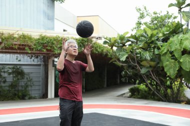Basketbol sahasında basketbol oynayan neşeli, aktif, son sınıf öğrencisi..