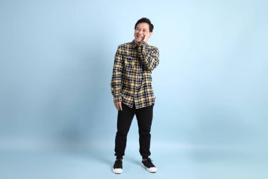 Diş teli takan, sıradan bir tişört giyen, mavi arka planda diş ağrısı çeken Asyalı bir adam..