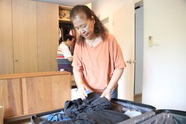 Üst düzey Doğu Asyalı çift yaklaşan yolculuklar için bavullarını hazırlıyor..