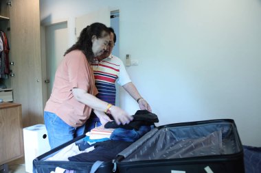 Üst düzey Doğu Asyalı çift yaklaşan yolculuklar için bavullarını hazırlıyor..