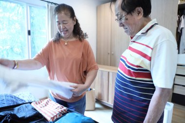 Üst düzey Doğu Asyalı çift yaklaşan yolculuklar için bavullarını hazırlıyor..