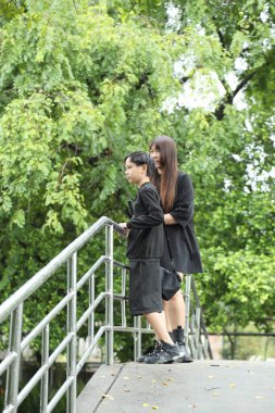 Asyalı bekar anne ve oğlu yağmur mevsiminde parkta birlikte vakit geçiriyorlar..