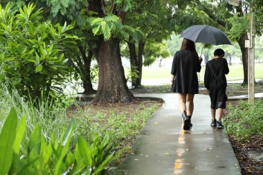 Asyalı bekar anne ve oğlu yağmur mevsiminde parkta birlikte vakit geçiriyorlar..