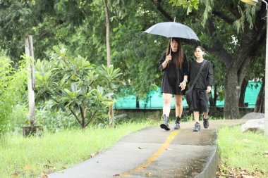 Asyalı bekar anne ve oğlu yağmur mevsiminde parkta birlikte vakit geçiriyorlar..