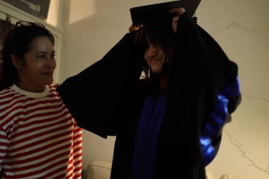 Bekar bir Asyalı anne kızının mezuniyetini gece kutluyor. Düşük tuşlu fotoğrafçılık.