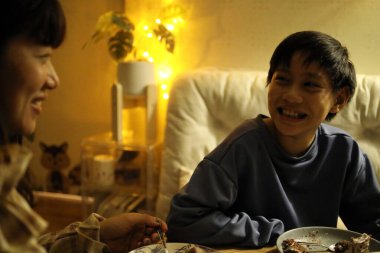 Bekar Asyalı anne, küçük oturma odasında oğlunun doğum gününü kutluyor..