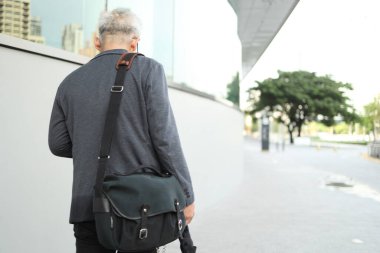 Akıllı telefon kullanan üst düzey bir Asyalı işadamı iş alanında yürüyor..