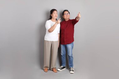 Gri bir arkaplan karşısında sıradan giyinmiş üst düzey bir Doğu Asyalı çift..