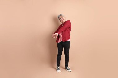 Kahverengi arka planda duran koyu kırmızı gömlekli kıdemli Doğu Asyalı adam..