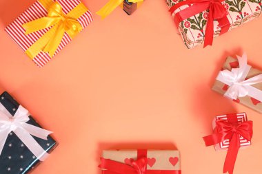 Şirin bir kağıda sarılmış ve fiyonklarla bağlanmış bir grup hediye kutusu kırmızı ya da pembe bir arka plana karşı dizilmiş, bir stüdyoda çekilmiş..