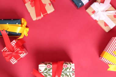 Şirin bir kağıda sarılmış ve fiyonklarla bağlanmış bir grup hediye kutusu kırmızı ya da pembe bir arka plana karşı dizilmiş, bir stüdyoda çekilmiş..