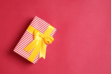 Şirin bir kağıda sarılmış ve fiyonklarla bağlanmış bir grup hediye kutusu kırmızı ya da pembe bir arka plana karşı dizilmiş, bir stüdyoda çekilmiş..