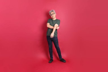 Beyaz tişörtlü üst düzey bir Doğu Asyalı koyu kırmızı arka planda duruyor..