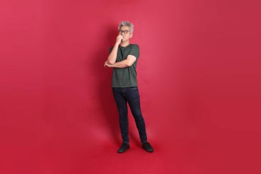 Beyaz tişörtlü üst düzey bir Doğu Asyalı koyu kırmızı arka planda duruyor..